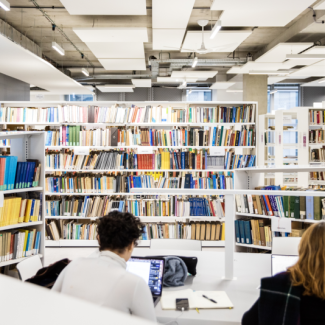Photo de l'intérieur de l'Humathèque, avec des personnes et des étagères de livres